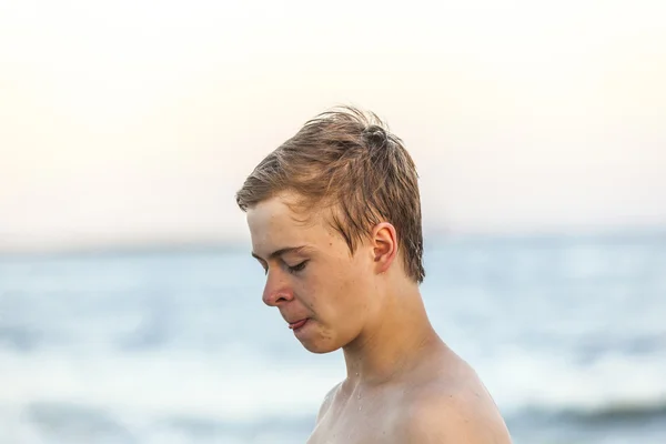 Guapo adolescente en la playa en la puesta del sol —  Fotos de Stock