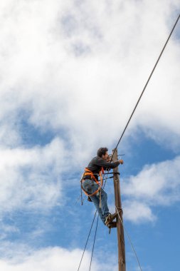 Lagoa, Portekiz - 31 Mart 2020: telekomünikasyon işçisi elektrik direğine fiberglas kabloyu yükledi.