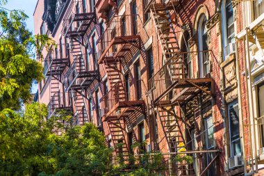 NEW YORK, ABD - OCT 5, 2017: New York 'taki eski tarihi bir evin cephesinde demir yangın merdiveni. 4 katlı ve daha fazla katlı her evin kanunen bir yangın merdivenine ihtiyacı vardı..