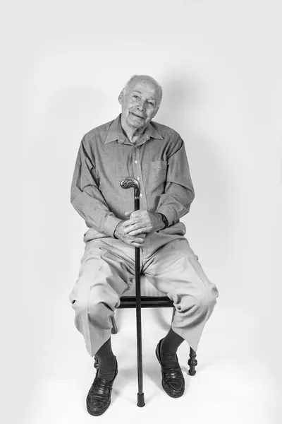 Ευτυχής Ηλικιωμένος Άνδρας Κάθεται Μπροστά Από Ένα Λευκό Φόντο — Φωτογραφία Αρχείου