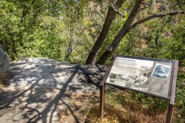 Three Rivers, USA - May 21, 2022: signage and rock with holes for burning fire in prehistoric indian kitchen..
