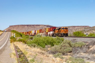 Valentine, USA May 25, 2022: diesel train with container passes the flat desert landscape.