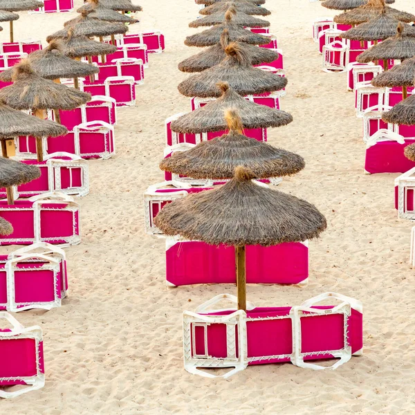 红色海滩沙发是早上在沙滩上 有稻草阳伞等待第一批游客在马略卡岛 — 图库照片