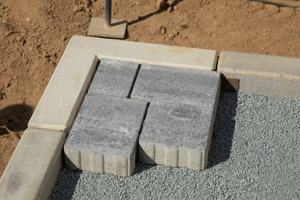 一个戴着手套的工匠把铺路石铺成层 在房子的四合院的沙质地基上铺灰色混凝土铺板 — 图库照片