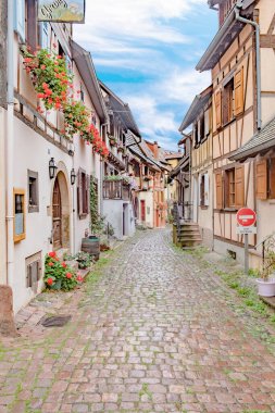 Eguisheim, Fransa - 4 Ekim 2021: Fransa 'nın Alsace bölgesindeki tarihi Eguisheim köyünde yarı ahşap evlere sahip manzaralı küçük yol.