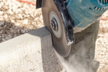 Kesici kaslı bir adam beton kaldırımı keser.