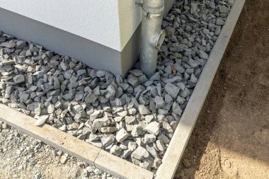 Kaldırımlar ve yağmur borusu ile inşa edilmiş yeni bir evin köşesinde çatı suyu toplanıyor.