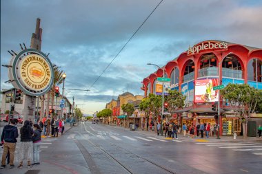 San Francisco, ABD - 5 Haziran 2022: İnsanlar şafak vakti San Francisco 'daki Balıkçı İskelesi' nin tadını çıkarıyorlar. Meşhur ışıklı tabela balıkçıların rıhtımlarını gösteriyor.
