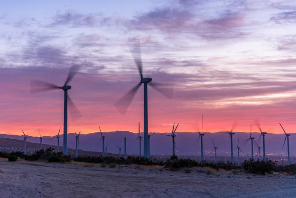 Power generating windmills in the mountains of Palm Springs, California at sunset spin as the strong winds pass by.