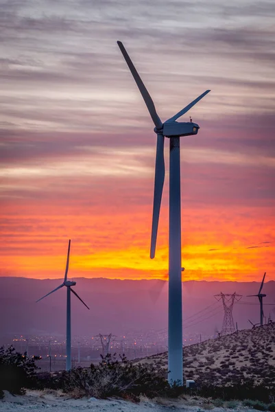 A wind generating turbine propellers await wind to form through a canyon as the sun rises to produce renewable energy.