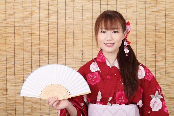 Молодая азиатка в кимоно держит бумажный вентилятор — стоковое фото