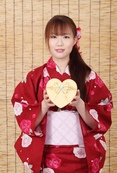 Молодая азиатка в кимоно с подарочной коробкой — стоковое фото