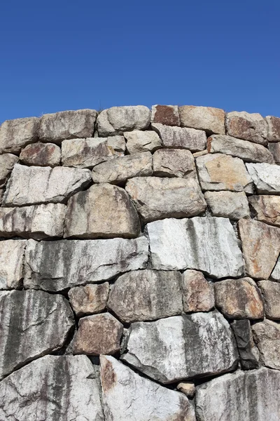 Vecchio muro di pietra contro il cielo blu chiaro — Foto Stock