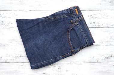 Beyaz ahşap arka planda katlanmış mavi kot, ahşap arka planda katlanmış kot. 