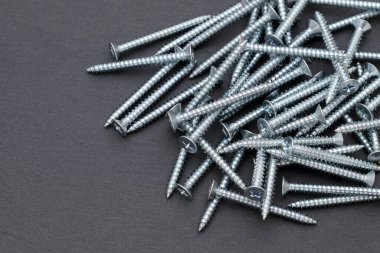 Siyah arka planda gümüş metalik vida yığını   