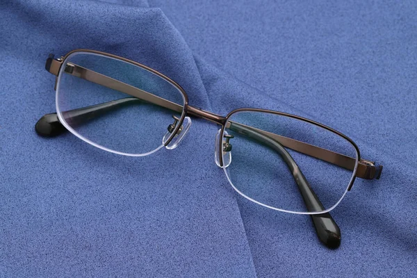 Stylish eyesight glasses and blue glass cleaning cloth background