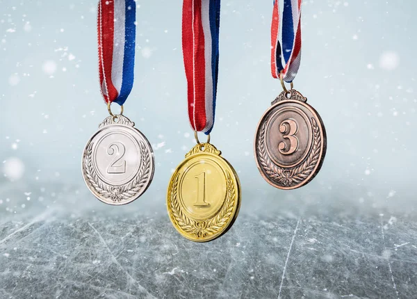 real Gold, silver and bronze medals hanging on red ribbons in an ice rink
