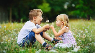 Mutlu çocuklar dışarıda karahindibalarla oynarlar.