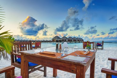 Gün batımında lüks plajda gözlüklü ve çatal bıçaklı bir masa..