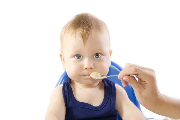 Ein junges grauäugiges Kind füttert Haferbrei — Stockfoto