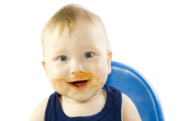 Hymyilevä sinisilmäinen lapsi ruokkii kurpitsan sose — kuvapankkivalokuva