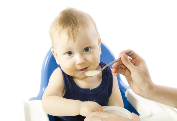 Ein junges grauäugiges Kind füttert Haferbrei — Stockfoto