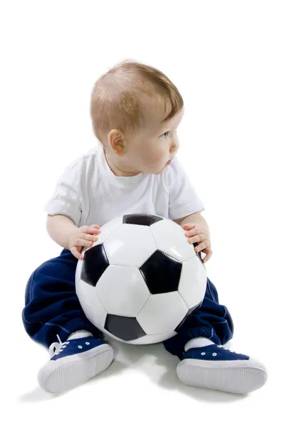 Barnet sitter på golvet med fotboll boll — Stockfoto