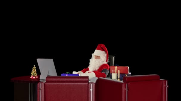 Der Weihnachtsmann bei der Arbeit, die Kontrolle von Blutdruck, gegen schwarz — Stockvideo