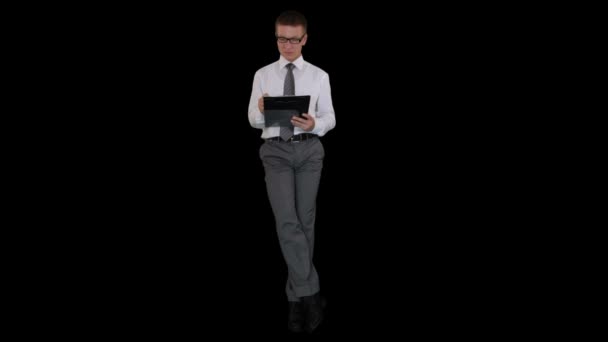 Young businessman with glasses writting on a clipboard and sitting, against black — Stock Video