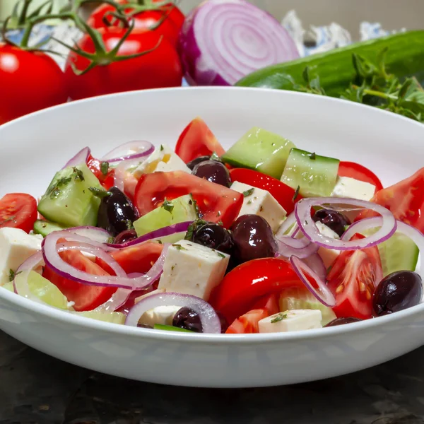 Görög Saláta Fehér Tálban Mögötte Hozzávalókkal Finom Mediterrán Ételek Stock Kép