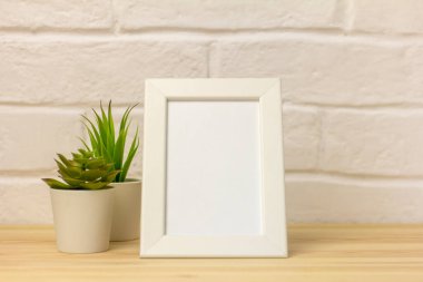 Rafta ya da masada sulu şeyler olan beyaz bir çerçeve yap. Tahta masa ve beyaz tuğla duvar