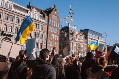 Hollanda, Amsterdam, 27.02.2022 Ukrayna 'da savaşa karşı bir gösteri. Rusya 'nın Ukrayna' yı işgaline karşı protesto. Savaş karşıtı şarkılar, pankartlar, pankartlar, Ukrayna bayrağı