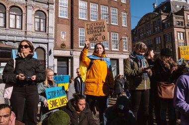 Hollanda, Amsterdam, 27.02.2022 Ukrayna 'da savaşa karşı bir gösteri. Rusya 'nın Ukrayna' yı işgaline karşı protesto. Savaş karşıtı şarkılar, pankartlar, pankartlar, Ukrayna bayrağı