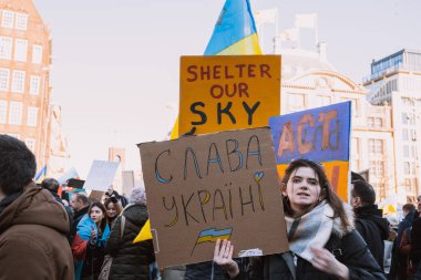 Hollanda, Amsterdam, 27.02.2022 Ukrayna 'da savaşa karşı bir gösteri. Rusya 'nın Ukrayna' yı işgaline karşı protesto. Savaş karşıtı şarkılar, pankartlar, pankartlar, Ukrayna bayrağı