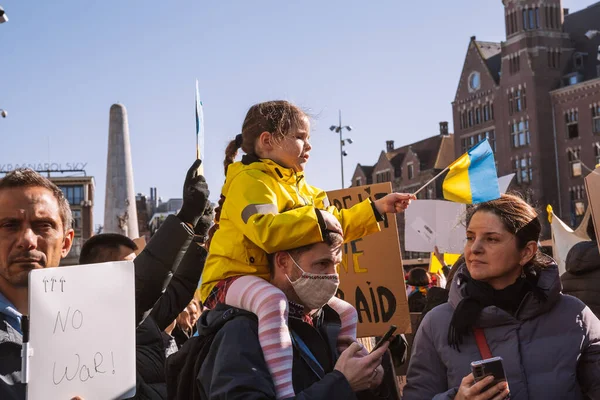 Hollanda, Amsterdam, 27.02.2022 Ukrayna 'da savaşa karşı bir gösteri. Rusya 'nın Ukrayna' yı işgaline karşı protesto. Savaş karşıtı şarkılar, pankartlar, pankartlar, Ukrayna bayrağı
