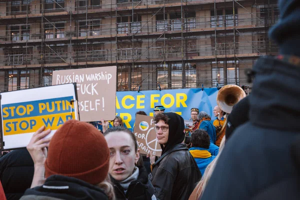 Hollanda, Amsterdam, 27.02.2022 Ukrayna 'da savaşa karşı bir gösteri. Rusya 'nın Ukrayna' yı işgaline karşı protesto. Savaş karşıtı şarkılar, pankartlar, pankartlar, Ukrayna bayrağı