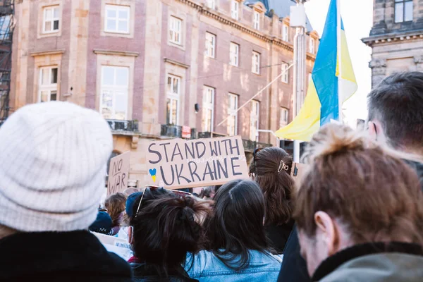 Hollanda, Amsterdam, 27.02.2022 Ukrayna 'da savaşa karşı bir gösteri. Rusya 'nın Ukrayna' yı işgaline karşı protesto. Savaş karşıtı şarkılar, pankartlar, pankartlar, Ukrayna bayrağı