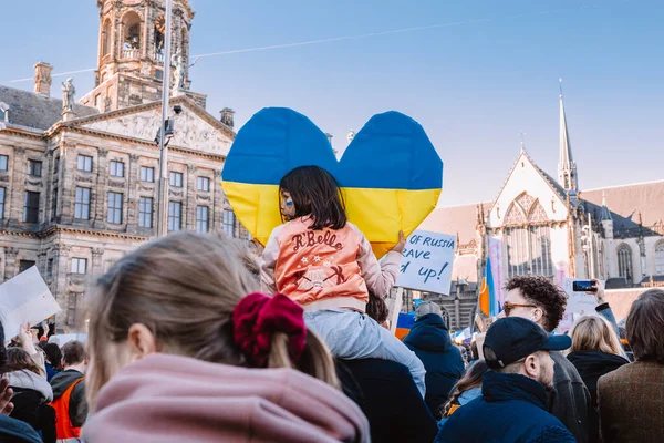 Hollanda, Amsterdam, 27.02.2022 Ukrayna 'da savaşa karşı bir gösteri. Rusya 'nın Ukrayna' yı işgaline karşı protesto. Savaş karşıtı şarkılar, pankartlar, pankartlar, Ukrayna bayrağı