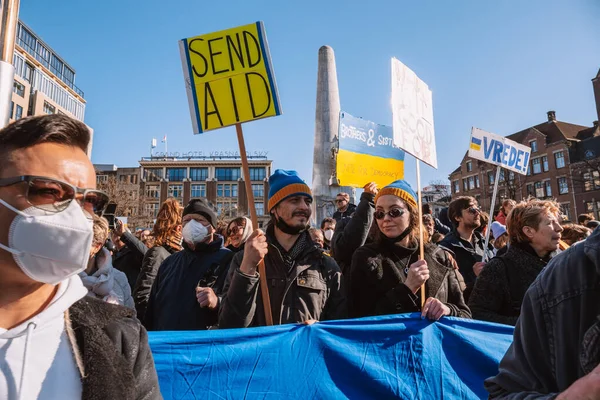 Hollanda, Amsterdam, 27.02.2022 Ukrayna 'da savaşa karşı bir gösteri. Rusya 'nın Ukrayna' yı işgaline karşı protesto. Savaş karşıtı şarkılar, pankartlar, pankartlar, Ukrayna bayrağı