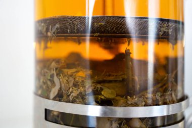 Fransız pres bardağı çaydanlığında demlenen sıcak çay. Yakın plan demlenmiş çay yaprakları cam çaydanlıkta.