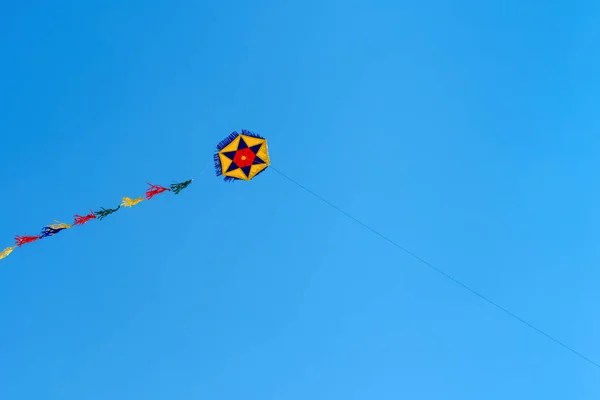 Renkli yuvarlak bir uçurtma gökyüzünde yükselir Mavi gökyüzünde. Spor uçurtma festivali. Yunanistan 'da temiz bir pazartesi. Kıvrılan kuyruklu uçan bir uçurtma. Kopyalama alanı