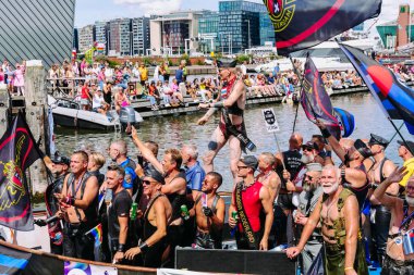 Pride Parade of lesbian, gay, bisexual, transgender, queer and allies. People s in leather bondage costumes with Gay leather and LGBT Progress Pride flags - Netherlands, Amsterdam, August 6, 2022