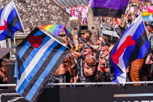 Pride Parade of lesbian, gay, bisexual, transgender, queer and allies. Mans in leather costumes with pansexual, non-binary and Gay leather, Puppy Pride flags - Netherlands, Amsterdam, August 6, 2022