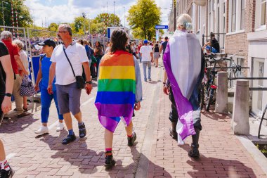 People wrapped up in lgbt pride flag and in asexual pride flag - lesbian, gay, bisexual, transgender, queer Pride Parade in Amsterdam, Netherlands - August 6, 2022.