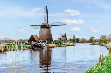 A row of water windmills on the river. Beautiful wind mills landscape. Windmill sails are moving by wind. Ecological energy.