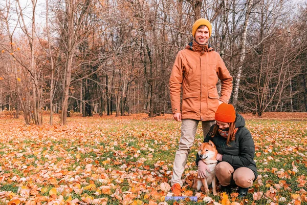 Family lovingly hugging dog. Sincere friendship with pet. Owners walk the dog in the park and patting it . Akita Inu breed. Mental health and stress relieve by pet. People hug dog.