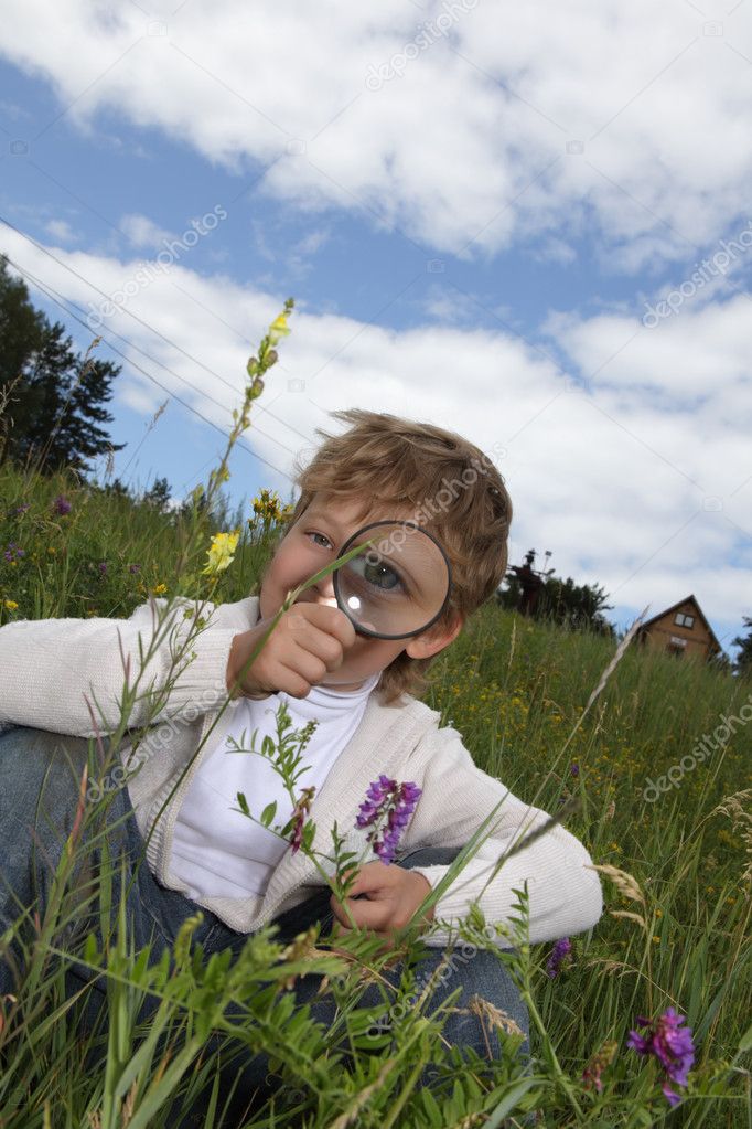 Boy with magnifying glass outdoors