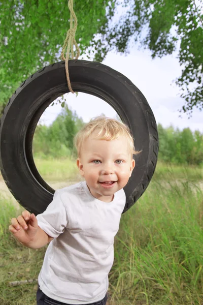 Счастливый мальчик на качелях — стоковое фото