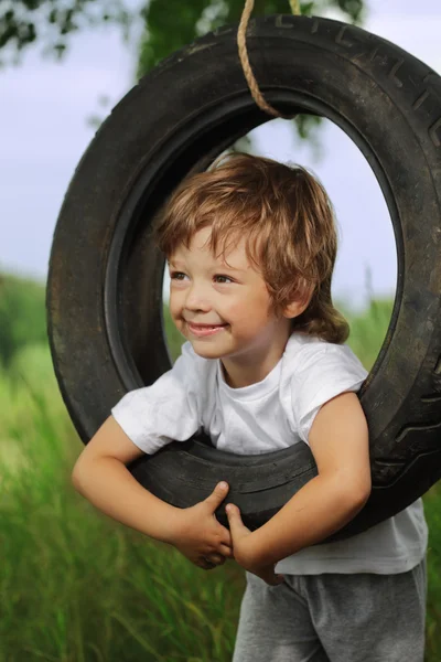 Счастливый мальчик на качелях — стоковое фото
