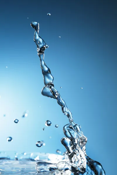 Salpicadura de agua sobre fondo azul — Foto de Stock